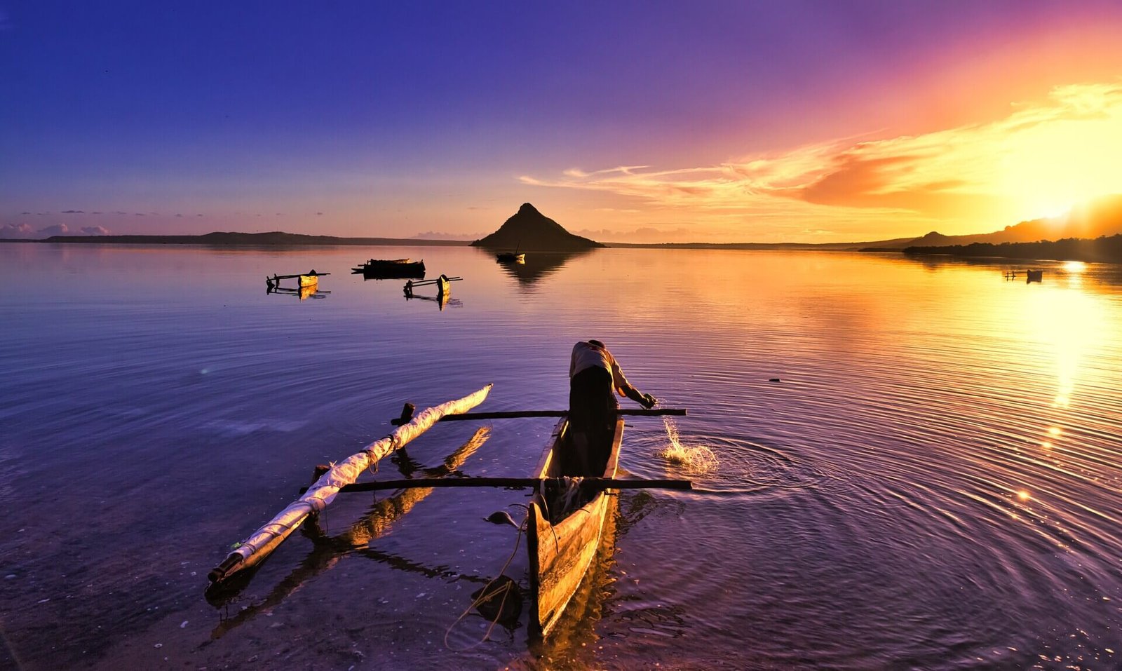 A boat floats on water at sunset