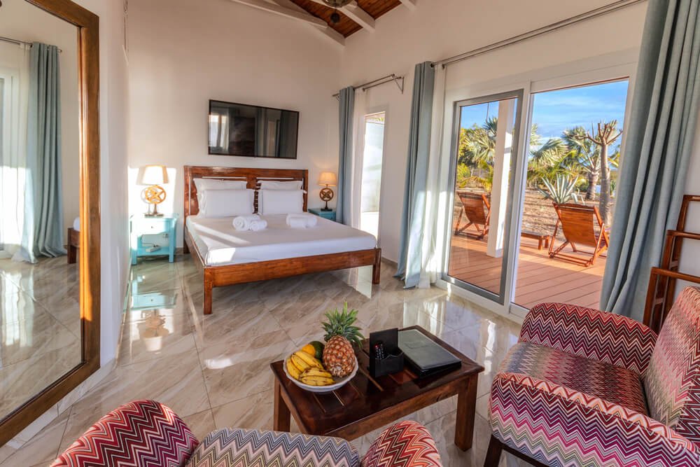A bright hotel room featuring a bed, armchairs