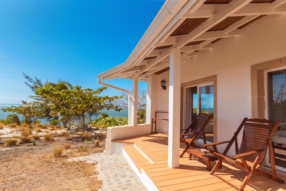 A porch featuring two chairs overlooks a serene ocean view