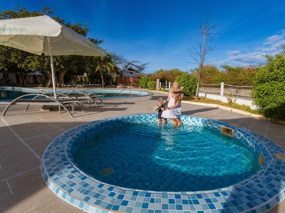 A woman in a white dress holds a child in a pool