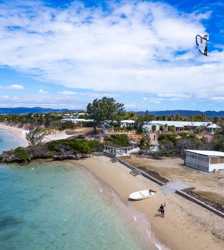 Aerial view of a sandy beach with a person holding a kite