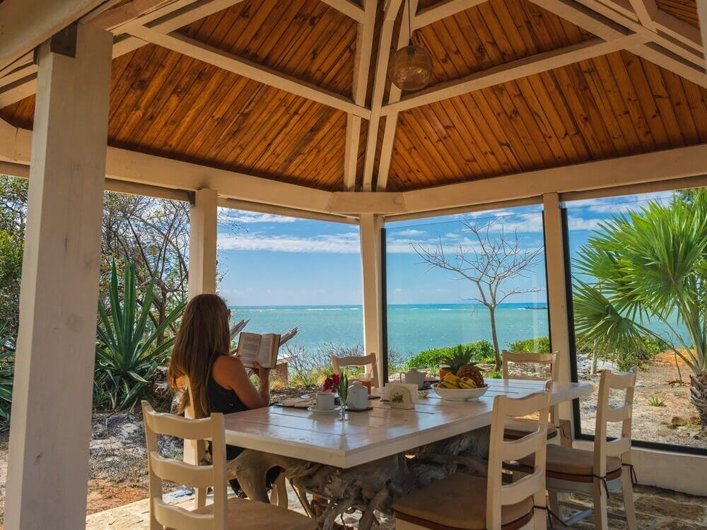 Woman reading peacefully in a sunlit beachfront gazebo